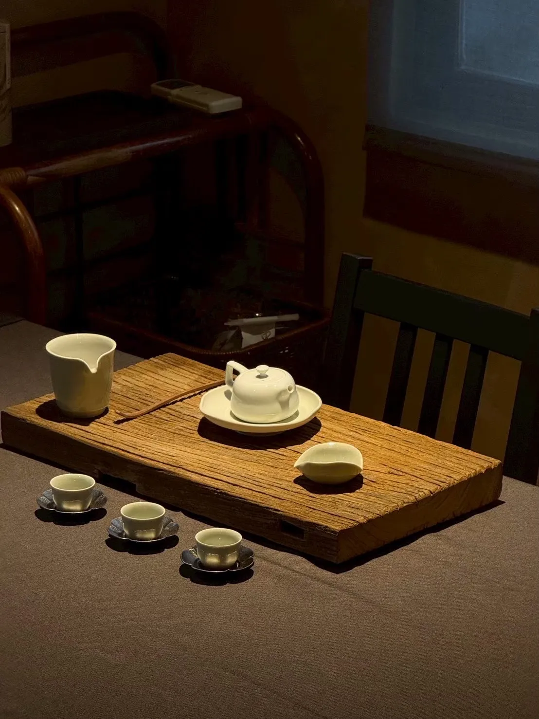 老木板上的白瓷茶壺、公道杯與三只茶杯
